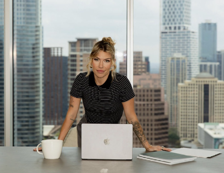 Kendall Strampel standing at a desk with a laptop in a downtown high rise office